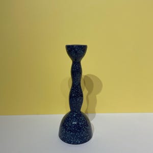 May include: A blue and white speckled ceramic candle holder with a unique, twisted design.