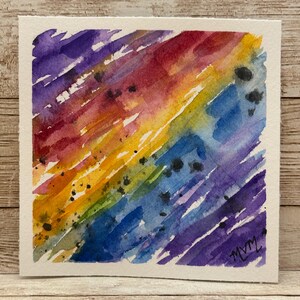 May include: Watercolor painting on white paper with diagonal brushstrokes in a rainbow of colors: purple, red, orange, yellow, green, and blue. Black paint splatters are scattered across the artwork. The artist's initials, MVM, are in the lower right corner.