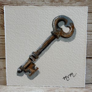 May include: Watercolor painting of an antique key. The key is brown with a blue-gray loop and a detailed bit. The artwork is on a square, off-white paper with the artist's signature in the lower right corner.