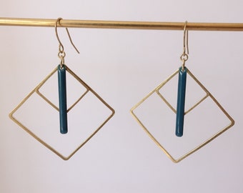 Peut inclure: Une paire de boucles d'oreilles géométriques dorées avec une barre de couleur turquoise suspendue à chacune. Les boucles d'oreilles sont en forme de diamant avec un plus petit diamant à l'intérieur.