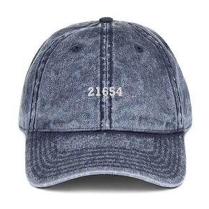 Può includere: Un cappello da baseball in denim blu con il numero "21654" ricamato in bianco sul davanti.