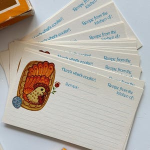 May include: A stack of vintage recipe cards with a colorful illustration of a hen and an egg. The cards have lines for writing recipes and the text "Here's what's cookin'" and "Recipe from the kitchen of:" printed in blue.