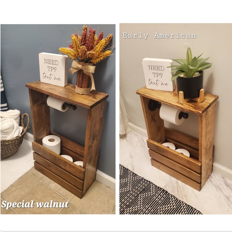 May include: A wooden bathroom storage unit in a special walnut finish. It features a top shelf with a decorative sign that reads "NEED TP? text me." The unit includes a toilet paper holder and a lower storage area for extra rolls.