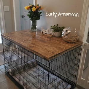 Pu&ograve; includere: Una gabbia per cani in filo metallico nero sormontata da una tavola di legno rettangolare tinta. La superficie ospita un vaso di vetro con rose gialle, un cartello in legno bianco con la scritta hello, una pianta verde e un barattolo.