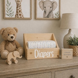 May include: A nursery scene with framed animal art, a wooden diaper holder labeled "Diapers", a teddy bear, and a wooden elephant. The decor is neutral with a soft, inviting aesthetic.