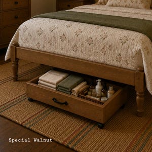 May include: A wooden under-bed storage drawer with a black handle and wheels, finished in a special walnut stain. The drawer contains folded beige and green towels, and a small wicker basket holding various bottles and containers.