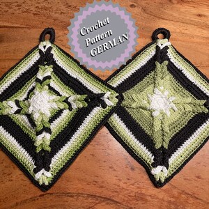 May include: Two crocheted pot holders in black, white and green with a diamond pattern. The pot holders have a loop at the top for hanging.