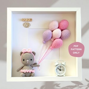 May include: A framed crochet art piece featuring a brown teddy bear holding pink and purple balloons. The frame also includes a wooden name block that reads "LISA" and a white alarm clock.