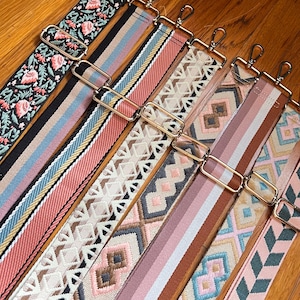 May include: Assortment of colorful woven straps with gold metal clasps. The straps feature various geometric patterns and colors, including pink, blue, brown, and white.