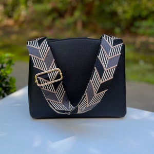 Make any purse, cell phone holder, or camera stylish with this black, grey, beige and gold adjustable strap with gold hardware clips. This guitar style Boho woven strap can make any purse or bag a crossbody. Choose one to go with our custom purses!