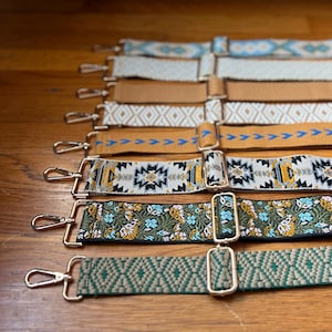 May include: A collection of seven adjustable bag straps featuring various woven patterns, including geometric shapes, floral motifs, and solid colours. Each strap is equipped with silver-toned metal swivel hooks and sliding buckles for length adjustment.