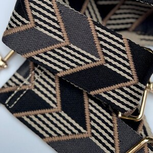Make any purse, cell phone holder, or camera stylish with this black, grey, beige and gold adjustable strap with gold hardware clips. This guitar style Boho woven strap can make any purse or bag a crossbody. Choose one to go with our custom purses!