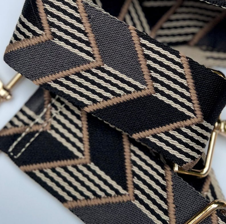 Make any purse, cell phone holder, or camera stylish with this black, grey, beige and gold adjustable strap with gold hardware clips. This guitar style Boho woven strap can make any purse or bag a crossbody. Choose one to go with our custom purses!