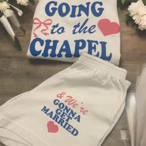 May include: White pajama set with the text "GOING to the CHAPEL" and a pink heart on the top. The matching shorts say "& We're GONNA GET MARRIED" with a pink heart. Perfect for a wedding.