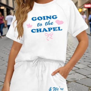 May include: White two-piece pajama set with the text "GOING to the CHAPEL" in blue, with pink accents. The shorts have the text "& We're GONNA GET MARRIED" in blue, with a pink heart. The set is perfect for a wedding.