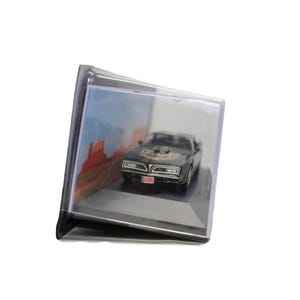May include: A black and gold miniature car model displayed in a clear plastic case. The car has a detailed design, including a hood emblem and license plate. The background features a desert landscape.