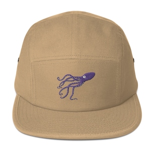 Könnte beinhalten: Eine beige 5-Panel-Kappe mit einem gestickten lila Kraken-Design.