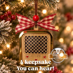 May include: A wooden ornament shaped like a vintage radio with a gold frame, a black speaker grille, and three small red heart accents. It is topped with a red and white gingham bow and a red bead, hanging from a brown cord with the text A keepsake You can hear!