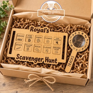 May include: A wooden scavenger hunt board with ten engraved squares labeled grass, pine cone, bark, flower, pine needles, stick, yellow leaf, rock, clover, and brown leaf, plus a matching wooden magnifying glass with animal tracks engraved around the lens.