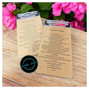 May include: Two wooden clipboard signs with the text "The Server's Prayer" printed on them. The prayer is a lighthearted and humorous take on the challenges of being a server. The signs are a light brown color and have a natural wood grain.