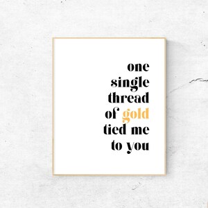 May include: A black and white typography print with the text "one single thread of gold tied me to you". The word "gold" is in a light orange color.