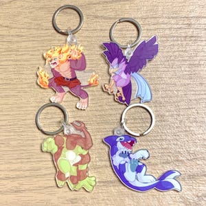 Puede incluir: Cuatro llaveros coloridos con personajes de animales de dibujos animados. Los llaveros están hechos de acrílico transparente y presentan un león, un pájaro, una tortuga y un delfín.