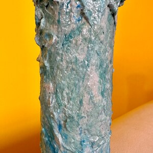 Pode incluir: Um vaso de cerâmica azul e branco com uma superfície texturizada. O vaso tem uma forma única e orgânica e é perfeito para exibir flores.