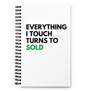 May include: A white spiral notebook with the text "EVERYTHING I TOUCH TURNS TO SOLD" in black. The word "SOLD" is in green.