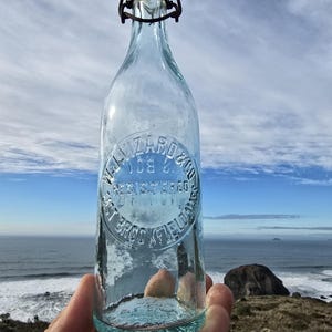 May include: A clear glass bottle with a wire bail closure. The bottle has a circular label that reads "Wizard Ice Co. Registered. Est. Bros. of Yelowas".