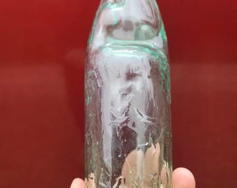 May include: A clear glass bottle with a green tint. The bottle has a rounded bottom and a narrow neck. The bottle is embossed with the text "WARNER'S" and "NY".