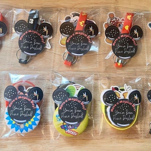 May include: Ten clear plastic bags each containing a set of Disney-themed party favors. Each bag includes a round sticker with Mickey Mouse ears and the text "Have a Magical Day! You've Been Pixie Dusted!" along with other Disney-themed stickers and a small keychain.