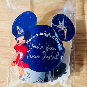 May include: A clear plastic bag with a Mickey Mouse head design. The bag contains a sticker with Mickey Mouse dressed as a wizard, a sticker with Tinkerbell, and a sticker with the text "Have a Magical Day! You've Been Pixie Dusted!"