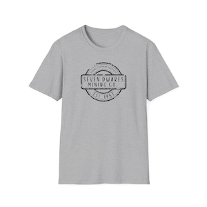 Op de afbeelding: Een heidegrijs T-shirt met een zwart-witte, verweerde stempelafbeelding met de tekst "Seven Dwarfs Mining Co. Est. 1951."