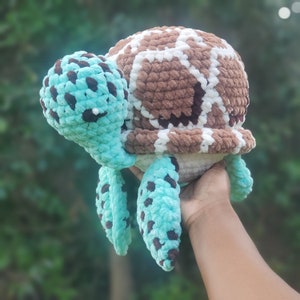 May include: A crocheted turtle toy with a brown and white shell and turquoise blue flippers.