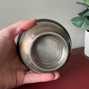 May include: A silver bowl with a smooth, shiny surface. The bowl is round and has a slightly raised rim.
