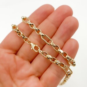 May include: A gold-colored chain bracelet with a lobster clasp. The bracelet features a mix of oval and rectangular links. The jewelry is displayed on a light background.