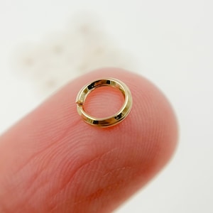 May include: A small, gold-colored jump ring. The ring is smooth and has a polished finish.
