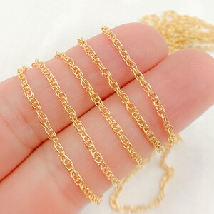 May include: Close-up of a gold chain, showing different lengths and widths. The chain is made of a delicate, twisted design.
