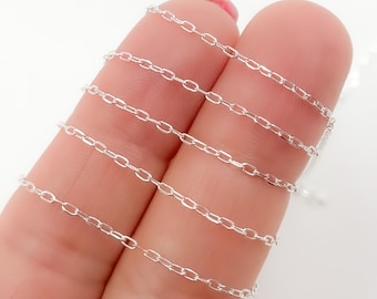 May include: A close-up of a silver chain, showing the links and texture. The chain is wrapped around two fingers.