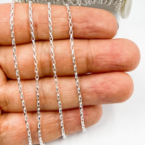 May include: Four strands of silver chain, each with a square link design, are displayed on a hand. The chains are approximately 18 inches long.
