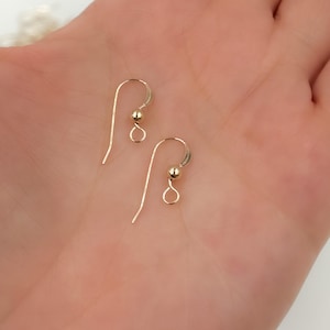 May include: Two gold-toned earring hooks with a small ball at the end of each hook.