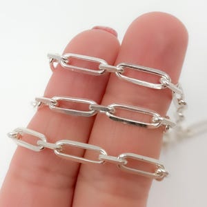 May include: Three silver chain necklaces with different sized oval links. The chains are layered on top of each other.