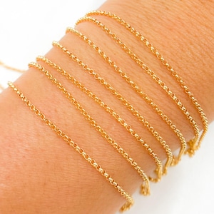 May include: A close-up of a gold chain necklace. The chain is shown in multiple sizes, layered on top of each other.