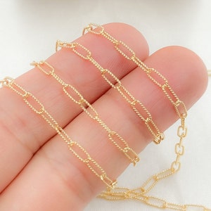 May include: Gold chain with a delicate, twisted, oval link design. The chain is shown in multiple layers, highlighting the intricate detail of the links.