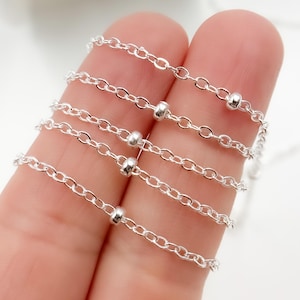 Puede incluir: Cinco cadenas de plata con pequeñas cuentas de plata, superpuestas.