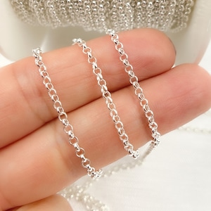 May include: Three silver chains of different sizes, shown on a hand. The chains are made of small, round links.