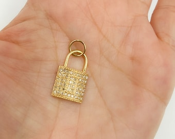 May include: A gold padlock charm with a square shape and a clear crystal design. The charm is small and delicate, perfect for adding a touch of sparkle to any jewelry piece.