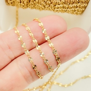 May include: Three strands of gold chain with a delicate, patterned design. The chain is made of small, round links with a textured surface.
