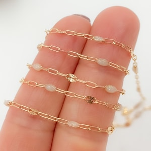 以下が含まれることがあります： 楕円形のビーズとテクスチャ加工された円形アクセントが特徴の繊細なゴールドチェーンネックレス。 ネックレスは細い長方形のリンクでできています。 このエレガントなジュエリーは、普段使いにも特別な機会にも適しています。