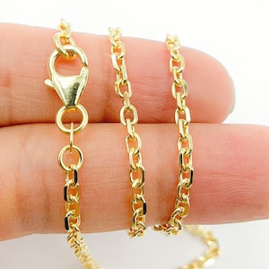 May include: Close-up of a gold-colored chain necklace with an oval link design. The necklace features a lobster clasp closure. The chain is displayed against a neutral background.